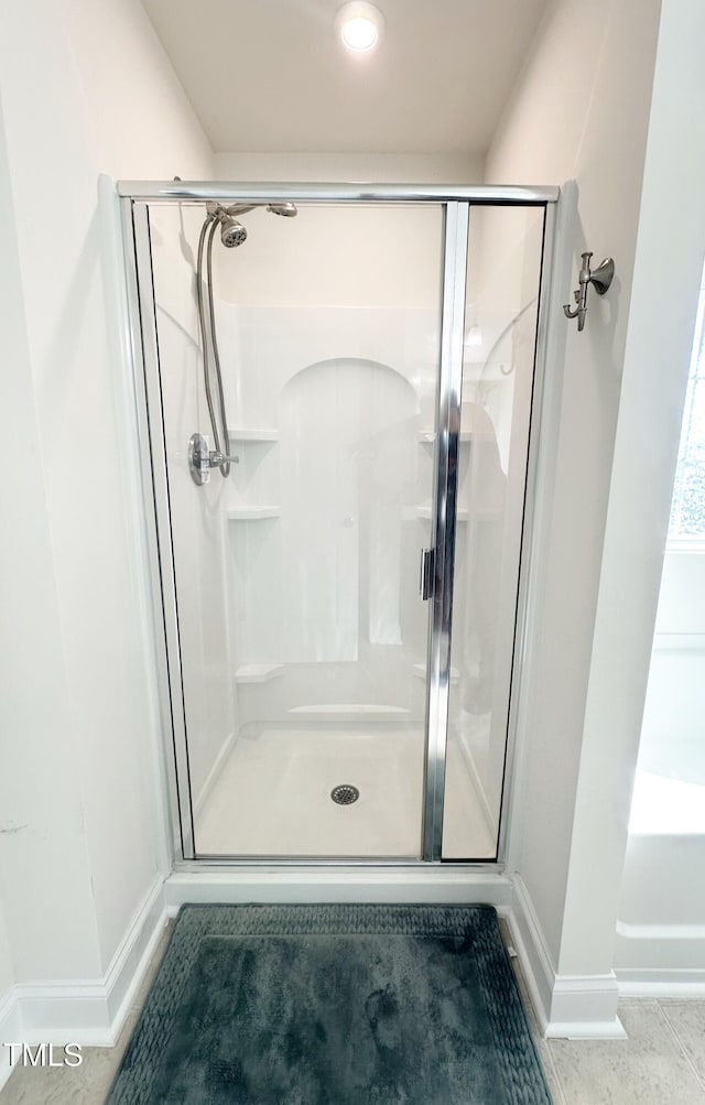 bathroom with a stall shower, tile patterned flooring, and baseboards