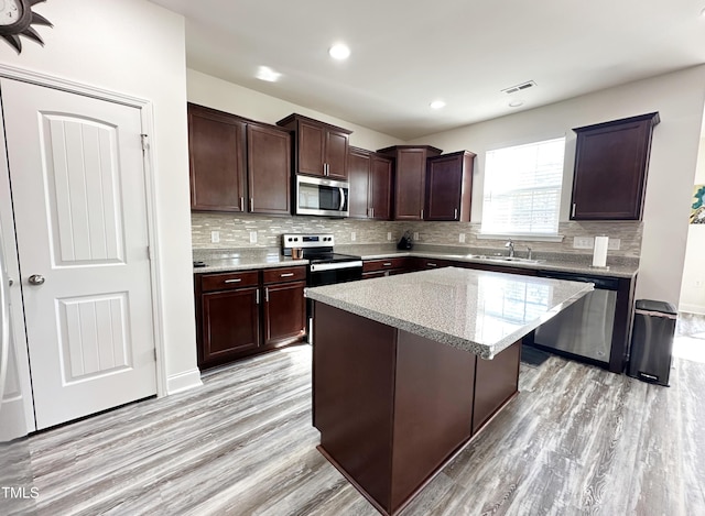 kitchen featuring stainless steel appliances, backsplash, a sink, and a center island