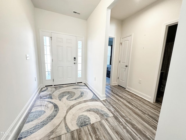 foyer featuring visible vents, baseboards, and wood finished floors