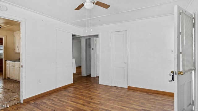 empty room featuring baseboards, attic access, a ceiling fan, and wood finished floors