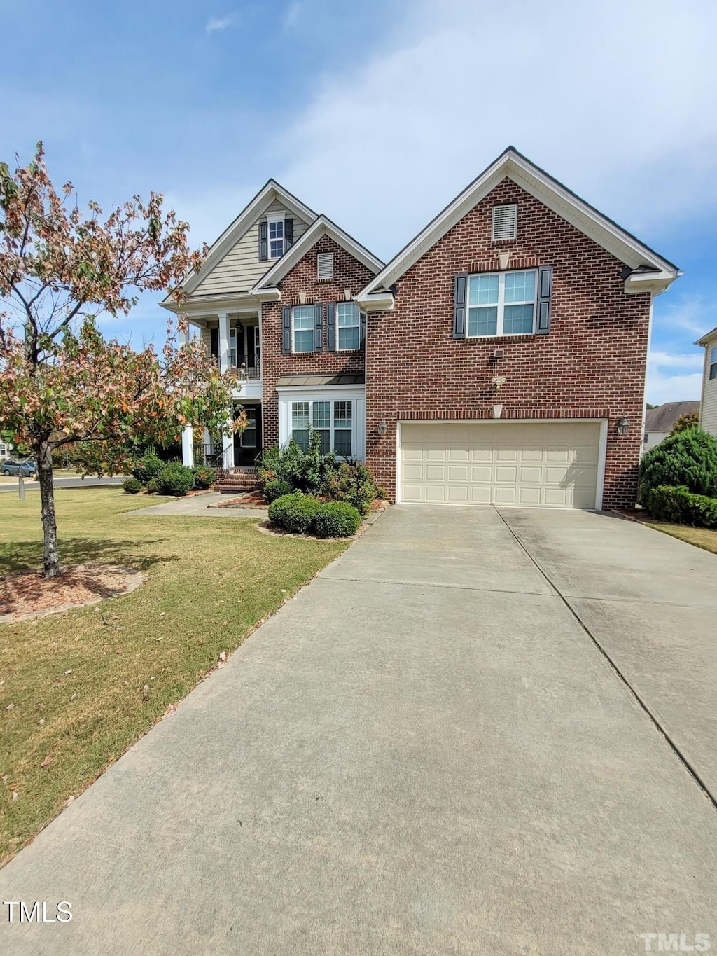 view of front facade featuring a garage, a front yard, brick siding, and driveway