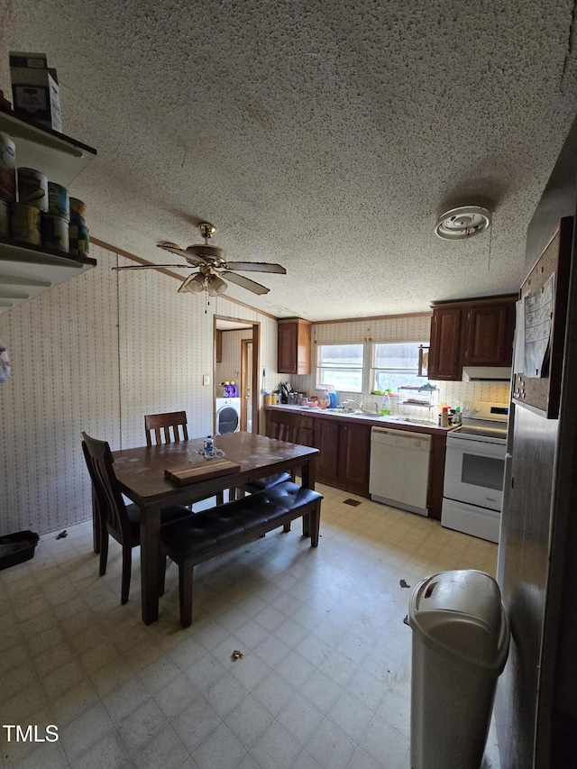 dining area with wallpapered walls, light floors, washer / clothes dryer, a textured ceiling, and a ceiling fan