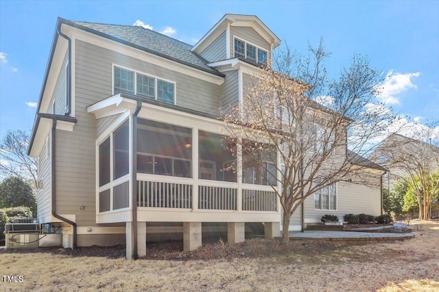 exterior space with a shingled roof and a sunroom