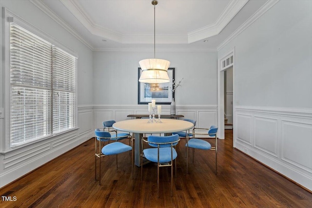 dining space featuring ornamental molding, wood finished floors, a raised ceiling, and a decorative wall