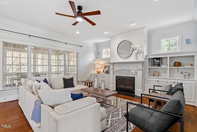 living room with baseboards, a ceiling fan, ornamental molding, wood finished floors, and a high end fireplace