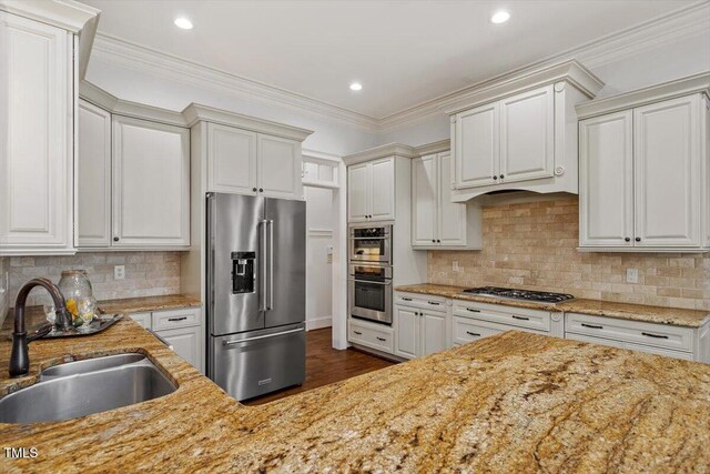 kitchen with tasteful backsplash, appliances with stainless steel finishes, light stone countertops, crown molding, and a sink