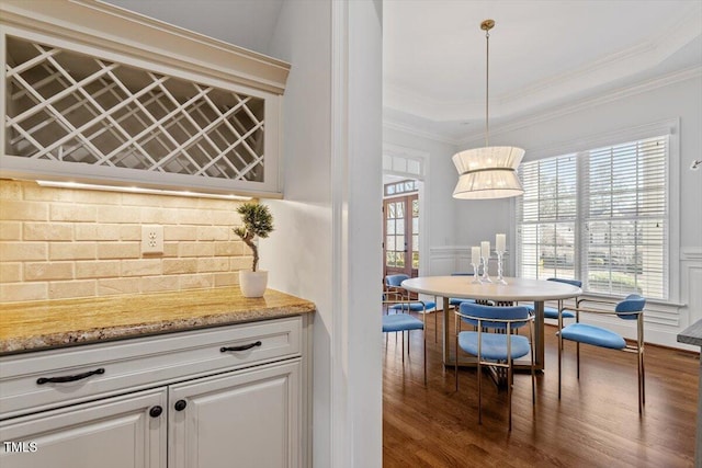 bar with plenty of natural light, wainscoting, wood finished floors, and crown molding