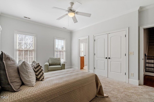 carpeted bedroom featuring visible vents, a closet, and ornamental molding