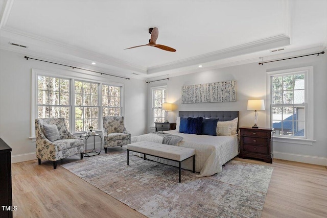 bedroom featuring a tray ceiling, visible vents, ornamental molding, wood finished floors, and baseboards