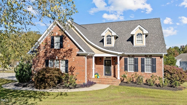 view of front of house featuring a shingled roof, a front yard, and brick siding