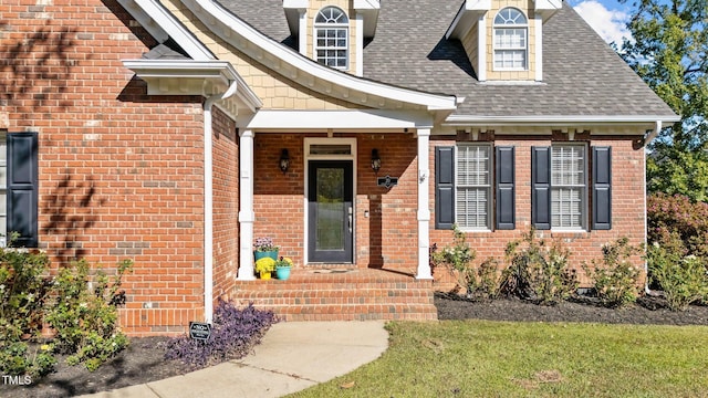 property entrance featuring a shingled roof and brick siding