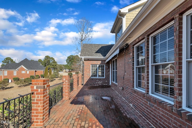 view of home's exterior with roof with shingles and brick siding