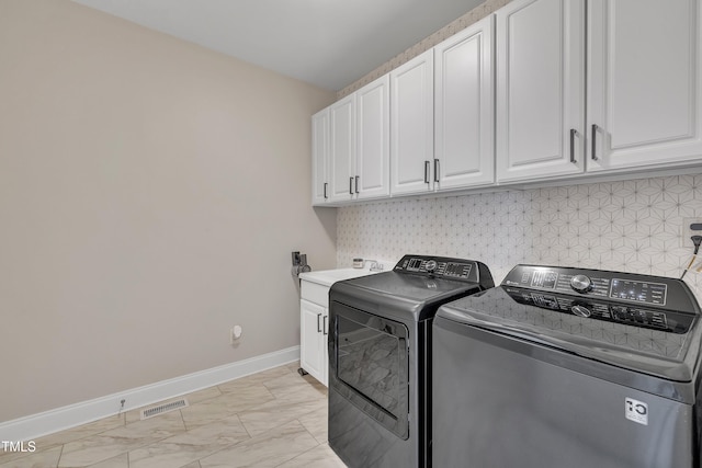 laundry area featuring marble finish floor, washer and clothes dryer, visible vents, cabinet space, and baseboards