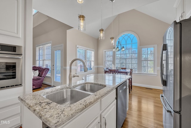 kitchen with white cabinets, light wood-style flooring, stainless steel appliances, and a sink