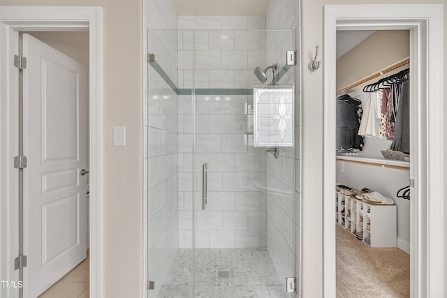 full bathroom with a walk in closet, a shower stall, and tile patterned floors