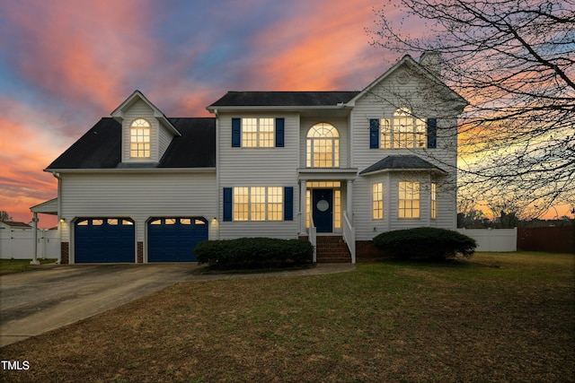 view of front facade with concrete driveway, a front lawn, an attached garage, and fence