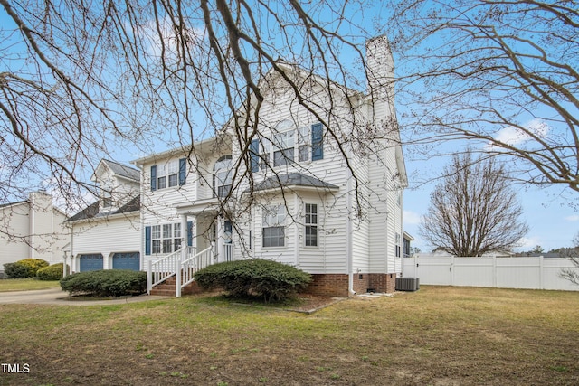 traditional-style home with a chimney, an attached garage, central AC, fence, and a front lawn