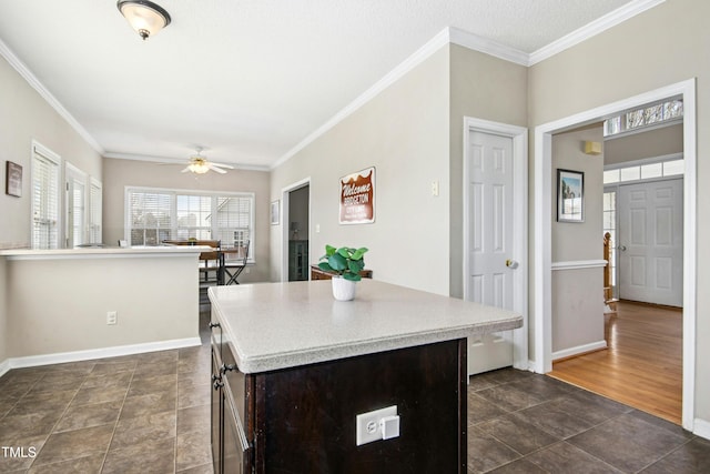 kitchen with light countertops, ornamental molding, and a ceiling fan