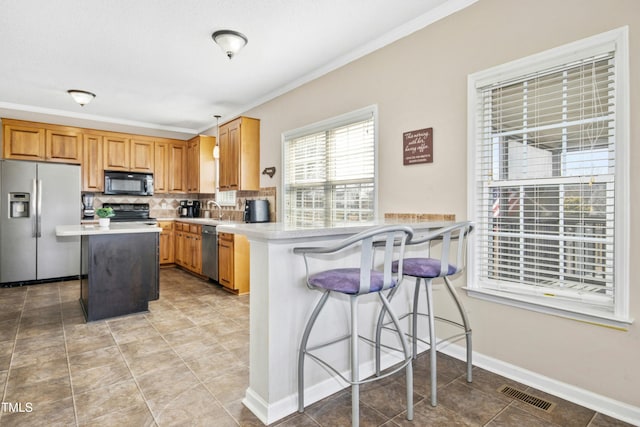 kitchen with crown molding, stainless steel appliances, light countertops, visible vents, and backsplash