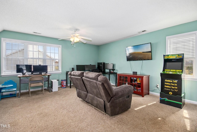 living area featuring baseboards, a textured ceiling, visible vents, and a ceiling fan