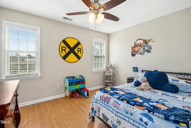 bedroom with a ceiling fan, baseboards, visible vents, and light wood finished floors