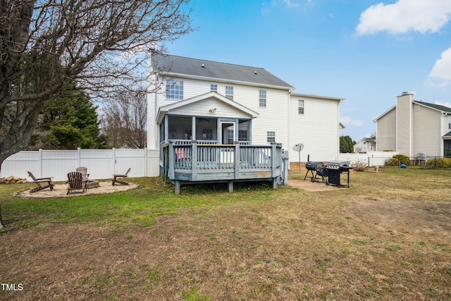 rear view of house featuring a sunroom, a fenced backyard, a yard, and a fire pit