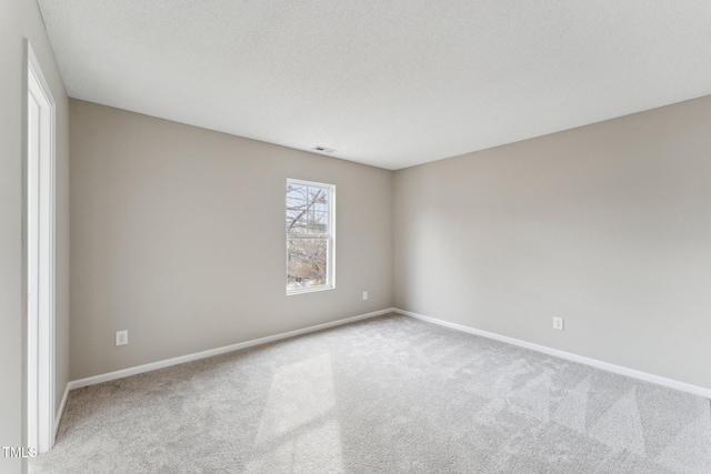 empty room featuring a textured ceiling, carpet flooring, visible vents, and baseboards