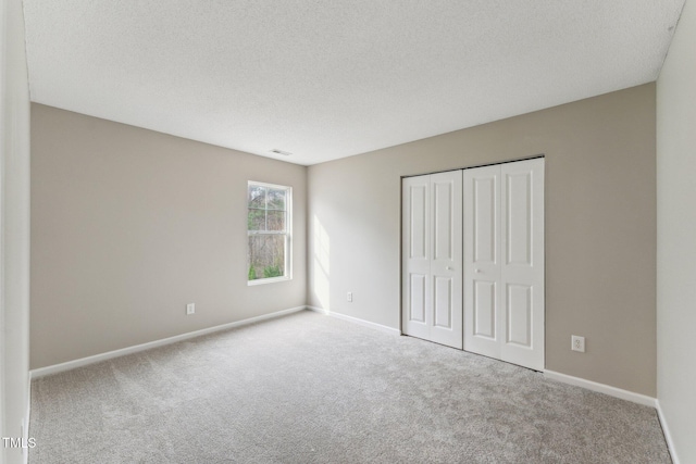 unfurnished bedroom featuring carpet floors, visible vents, a textured ceiling, and baseboards