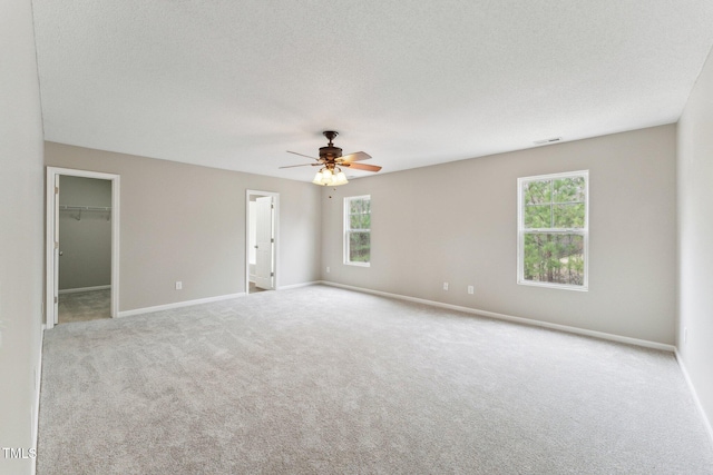 carpeted spare room with a ceiling fan, visible vents, a textured ceiling, and baseboards