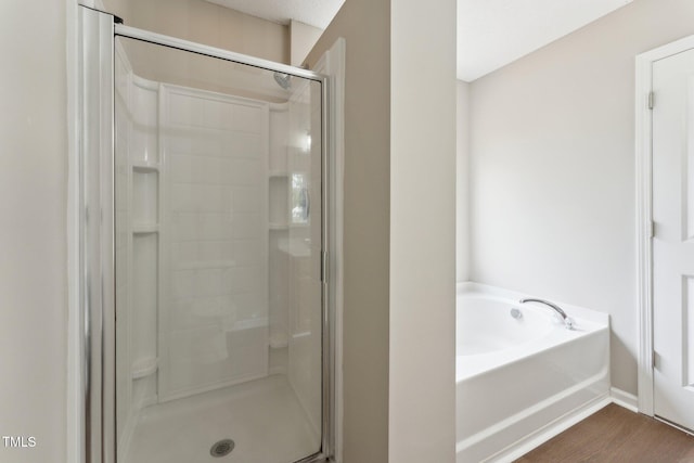 full bath featuring wood finished floors, a stall shower, and a garden tub