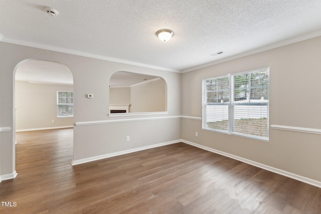 spare room featuring ornamental molding, visible vents, baseboards, and wood finished floors