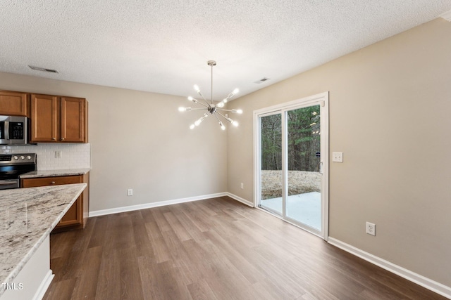 kitchen with brown cabinetry, visible vents, stainless steel appliances, and dark wood-style flooring