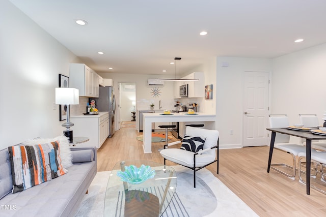 living area featuring light wood-style floors, recessed lighting, baseboards, and a wall mounted AC