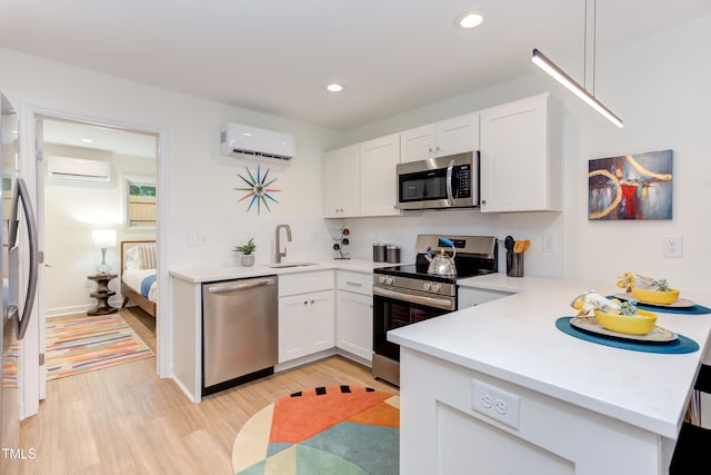 kitchen featuring appliances with stainless steel finishes, a wall mounted air conditioner, a sink, and a peninsula