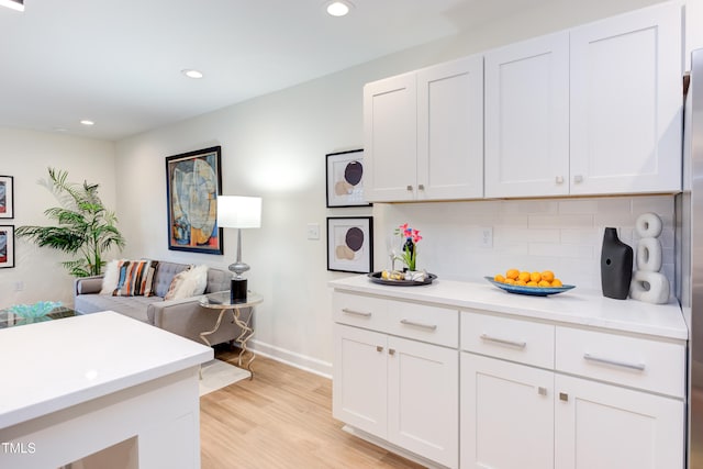 kitchen with white cabinets, light countertops, light wood-style floors, backsplash, and recessed lighting