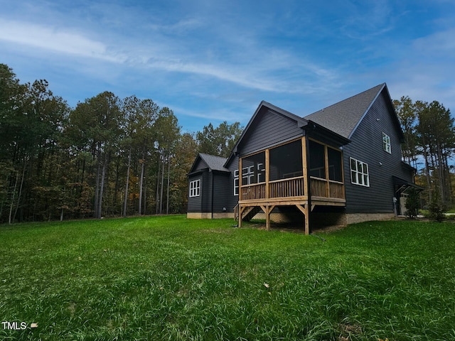 view of property exterior featuring a sunroom, roof with shingles, and a yard