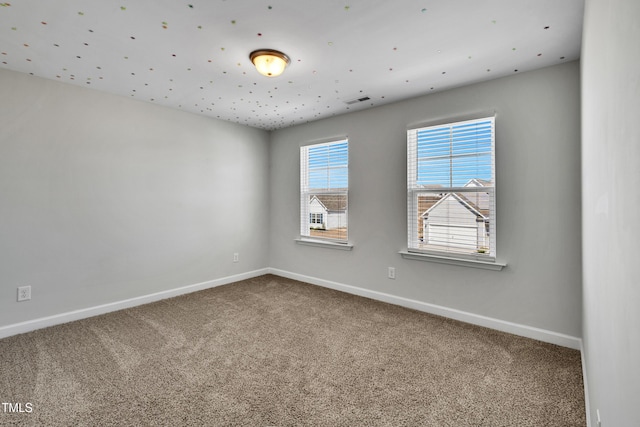 unfurnished room featuring carpet floors, visible vents, and baseboards