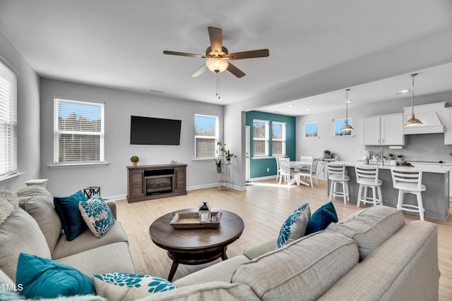 living room with baseboards, ceiling fan, light wood-type flooring, a fireplace, and recessed lighting