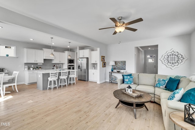 living room with light wood-type flooring, ceiling fan, baseboards, and recessed lighting