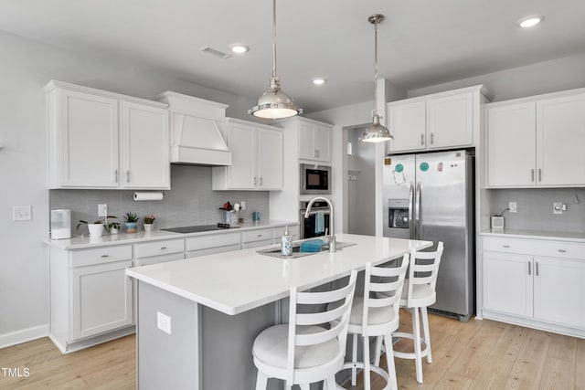 kitchen featuring appliances with stainless steel finishes, custom exhaust hood, light wood-style flooring, and white cabinets