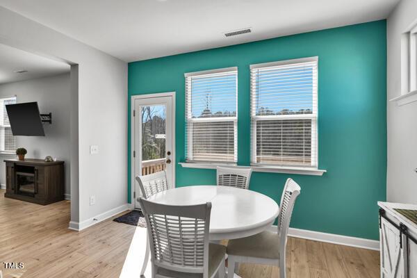 dining space with visible vents, light wood-style flooring, and baseboards