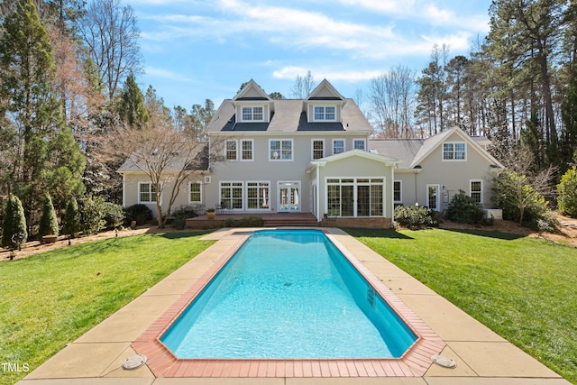 back of property featuring a yard, french doors, and an outdoor pool