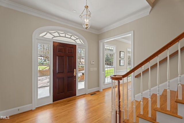 entrance foyer with baseboards, visible vents, stairway, crown molding, and light wood-type flooring