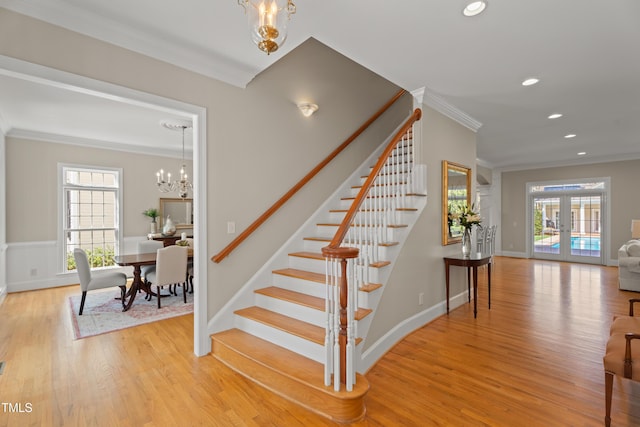 stairs featuring french doors, wood finished floors, a wealth of natural light, and crown molding