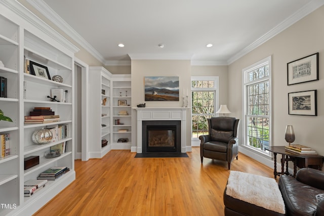 sitting room featuring ornamental molding, light wood finished floors, a fireplace with flush hearth, and recessed lighting