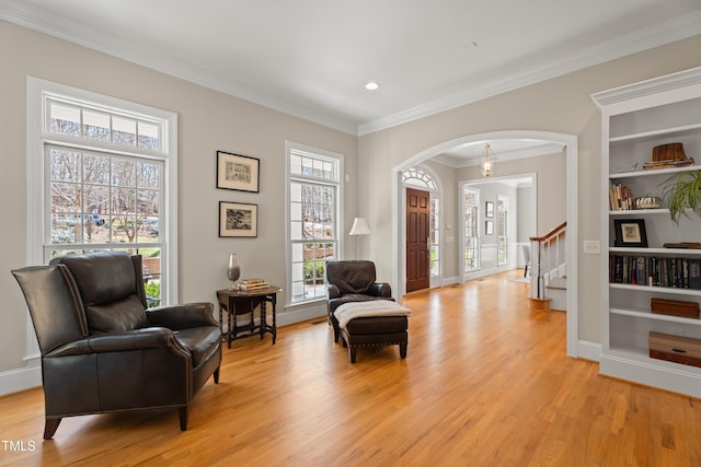 sitting room with arched walkways, baseboards, stairs, ornamental molding, and light wood-type flooring