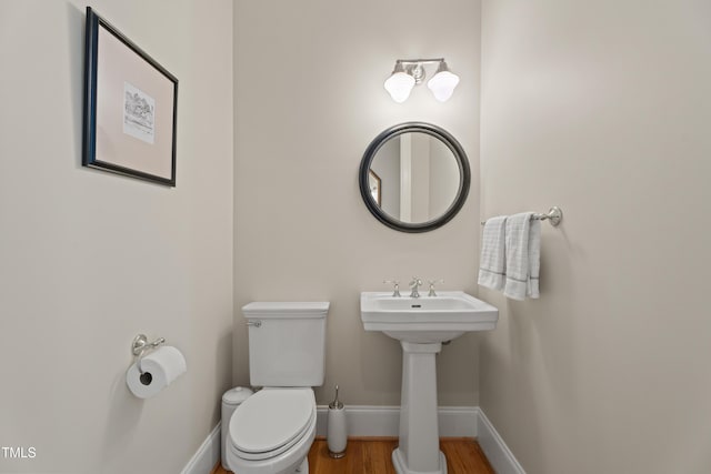 bathroom featuring a sink, toilet, baseboards, and wood finished floors