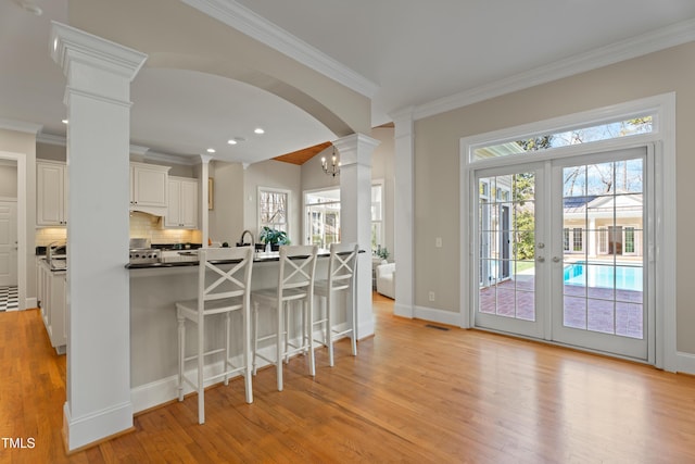 kitchen with a wealth of natural light, a breakfast bar area, decorative columns, and decorative backsplash