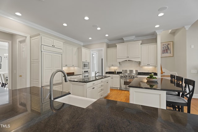 kitchen featuring appliances with stainless steel finishes, light wood-type flooring, a sink, and an island with sink