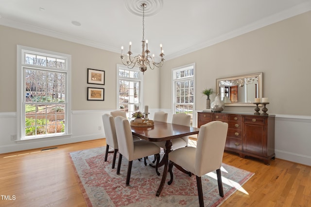 dining room featuring light wood-type flooring, a notable chandelier, crown molding, and visible vents